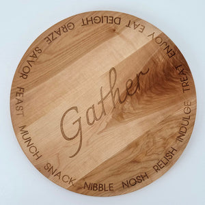 A round cherry hardwood serving board from an overhead view to display the typographically engraved design.