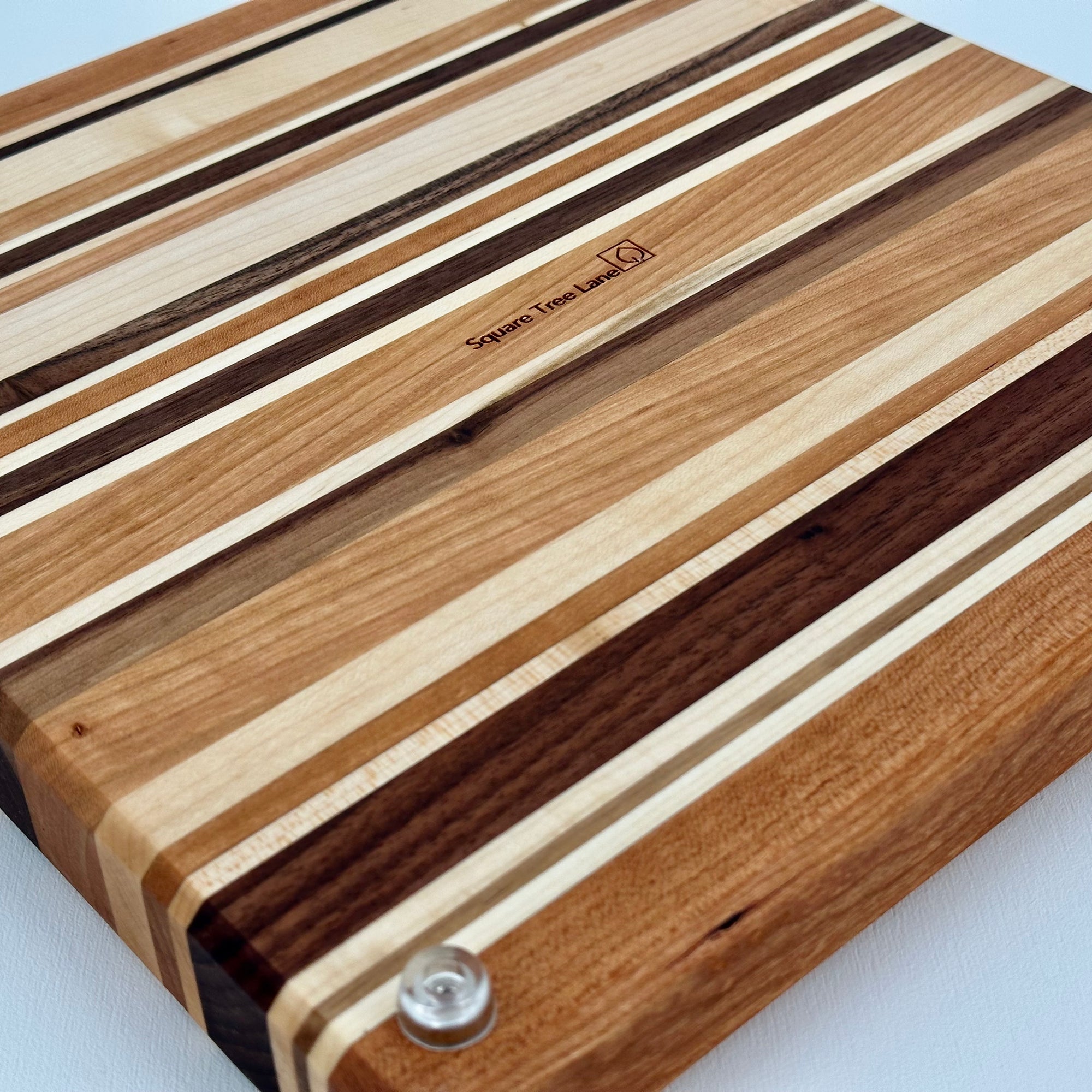 Wooden cutting board with striped pattern and visible brand logo on a white background